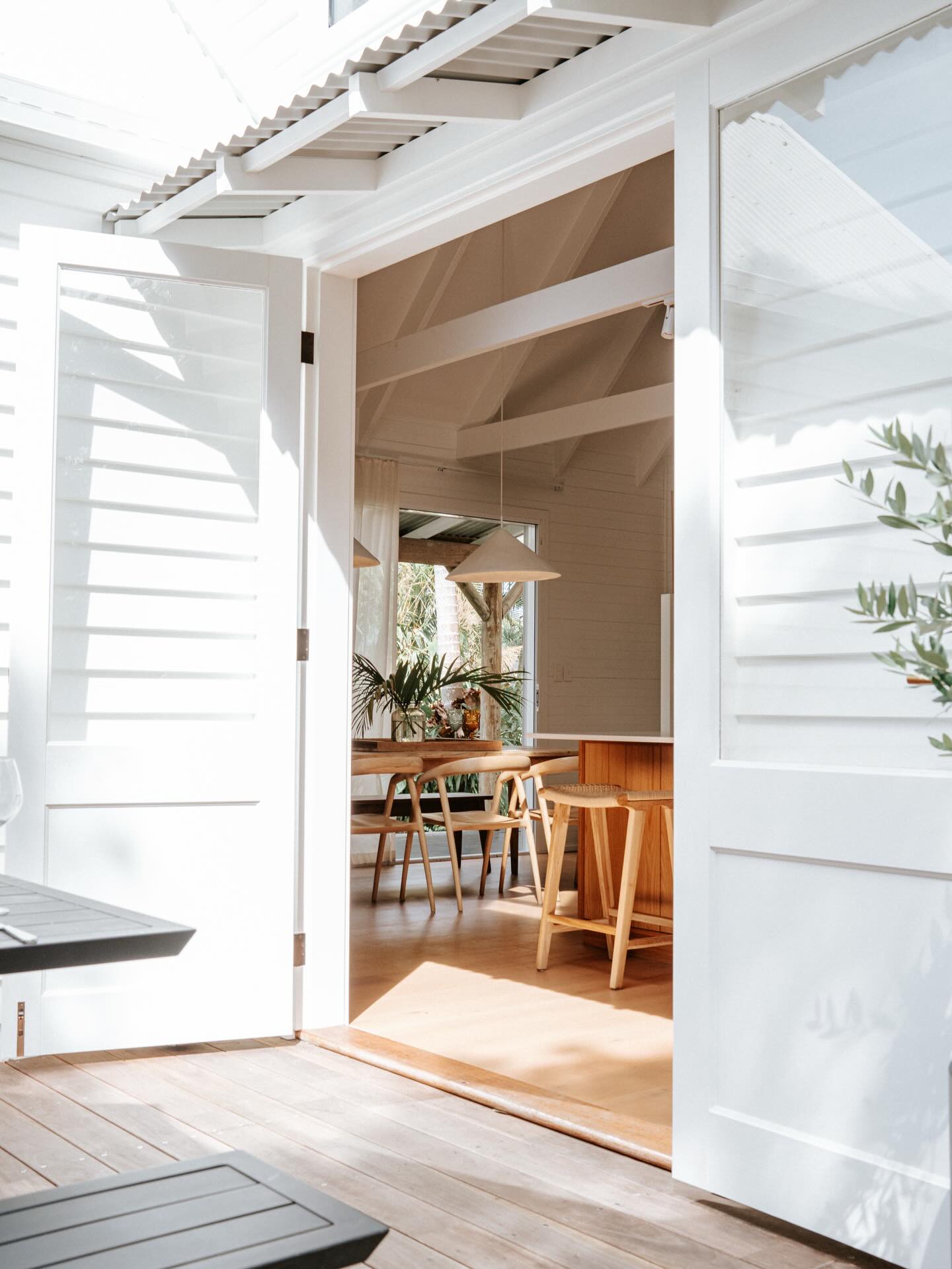 Open double doors looking through to a dining room with timber furniture