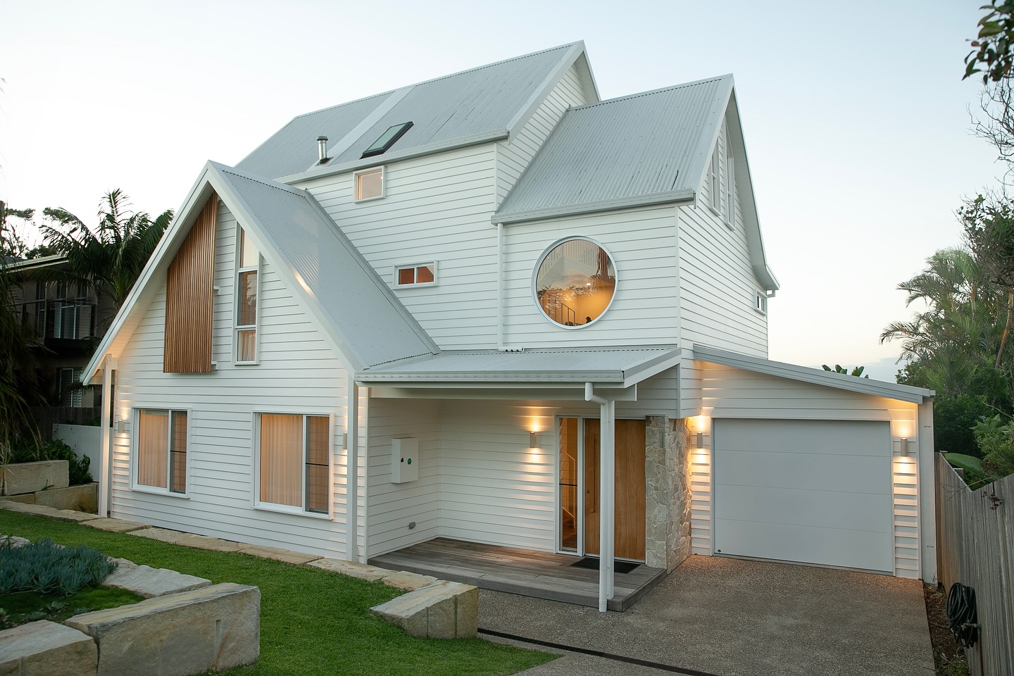 Three-storey white weatherboard house at Emerald Beach with a round feature window