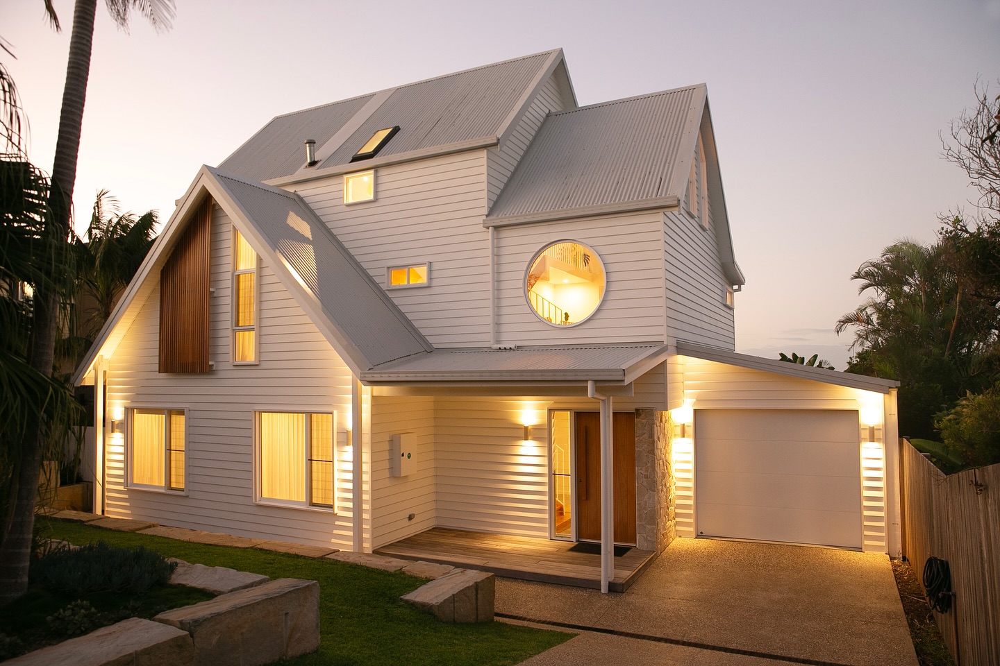 The completed renovation at dusk with warm light behind every window