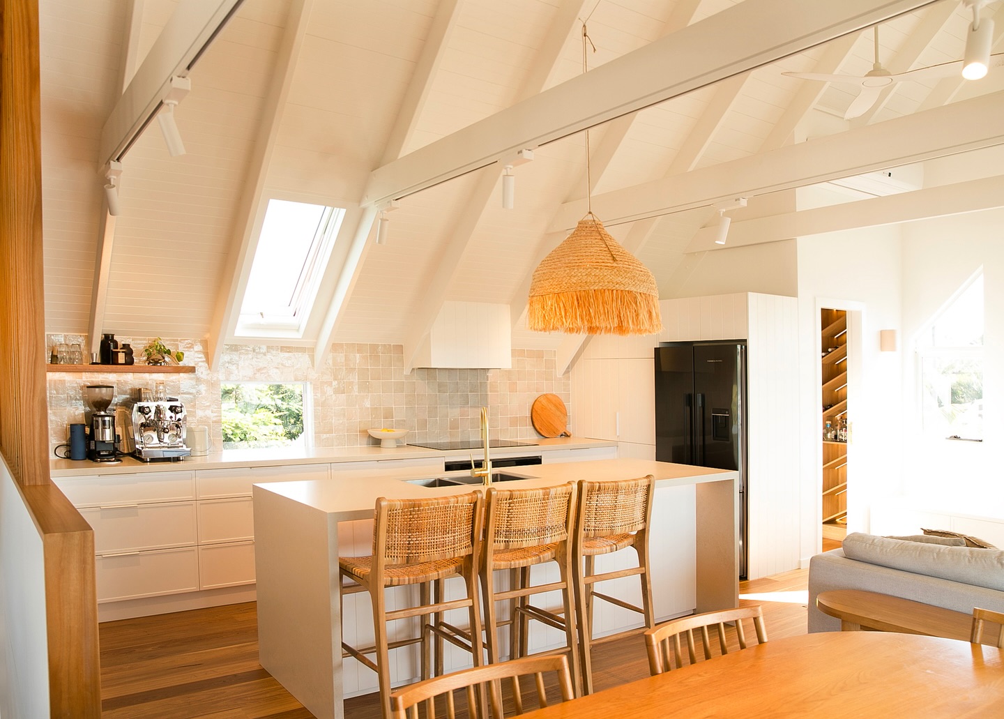 Vaulted white kitchen with exposed rafters, blonde timber floors and a woven pendant