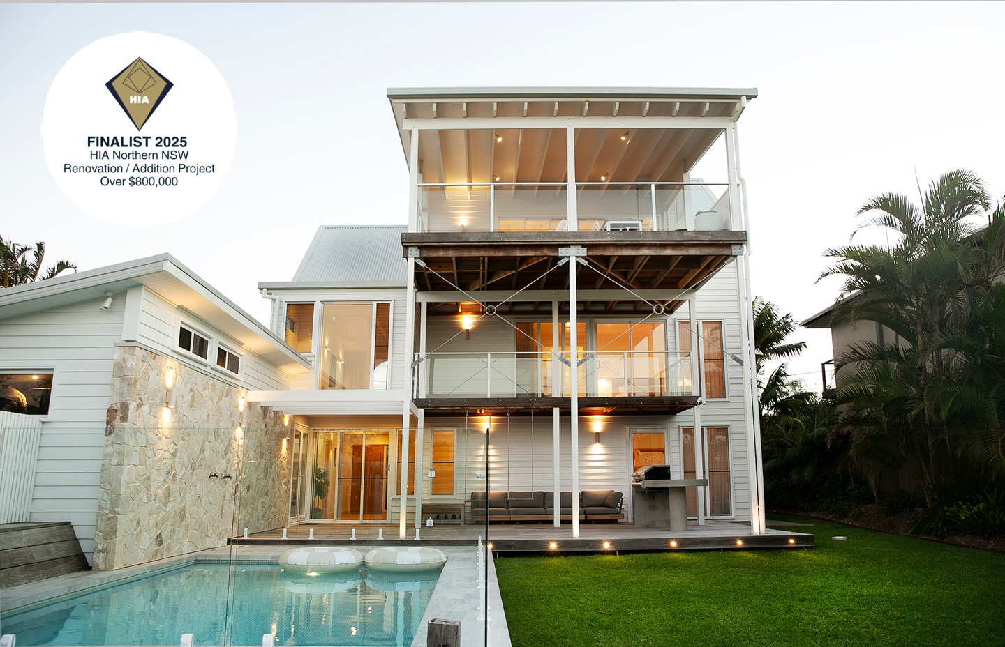 Rear elevation of a renovated three-storey weatherboard home with balconies above a pool