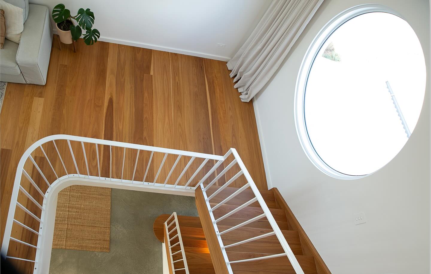 Stairwell and blonde timber floors beside a large round window