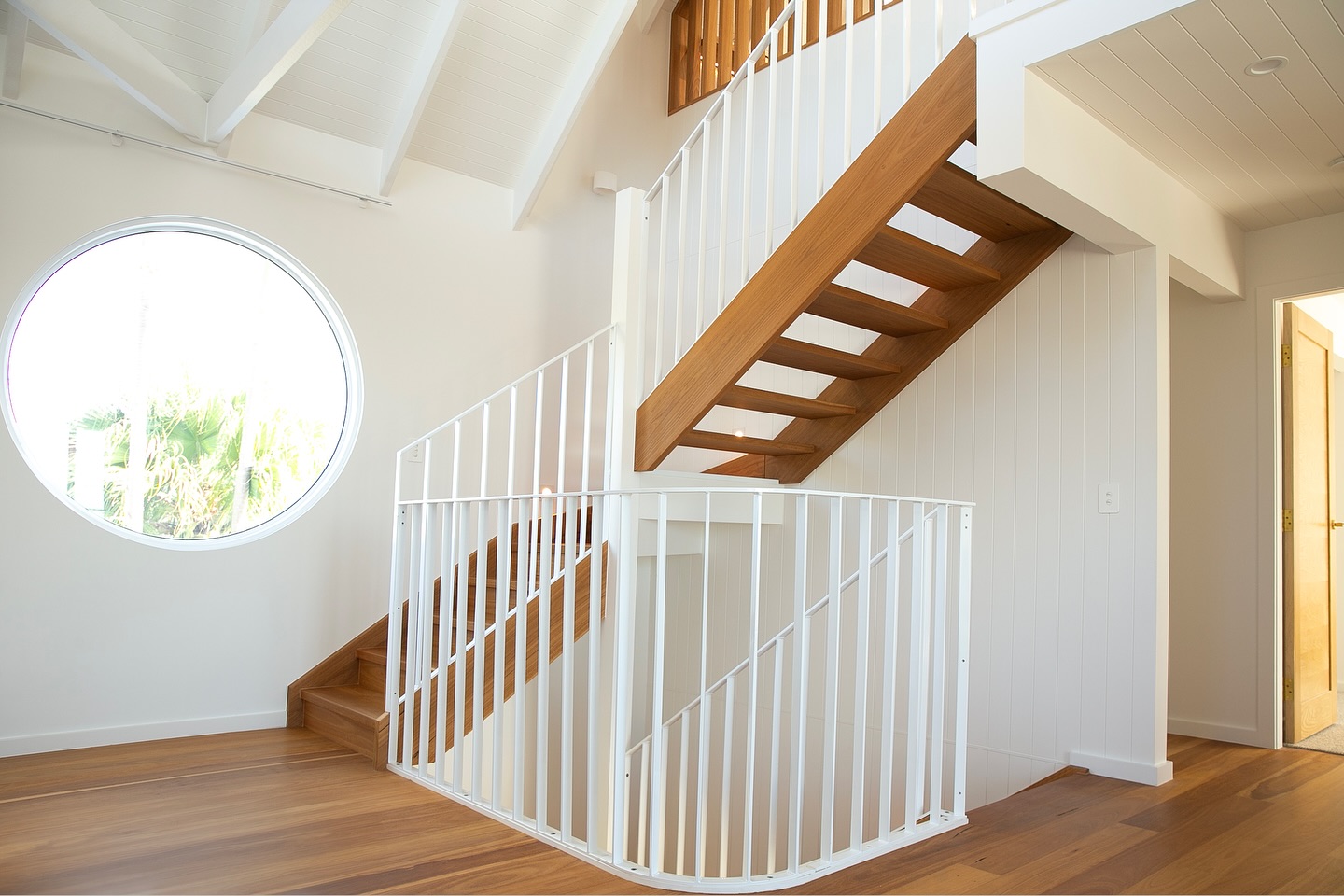Timber staircase with a white powder-coated steel balustrade against white walls